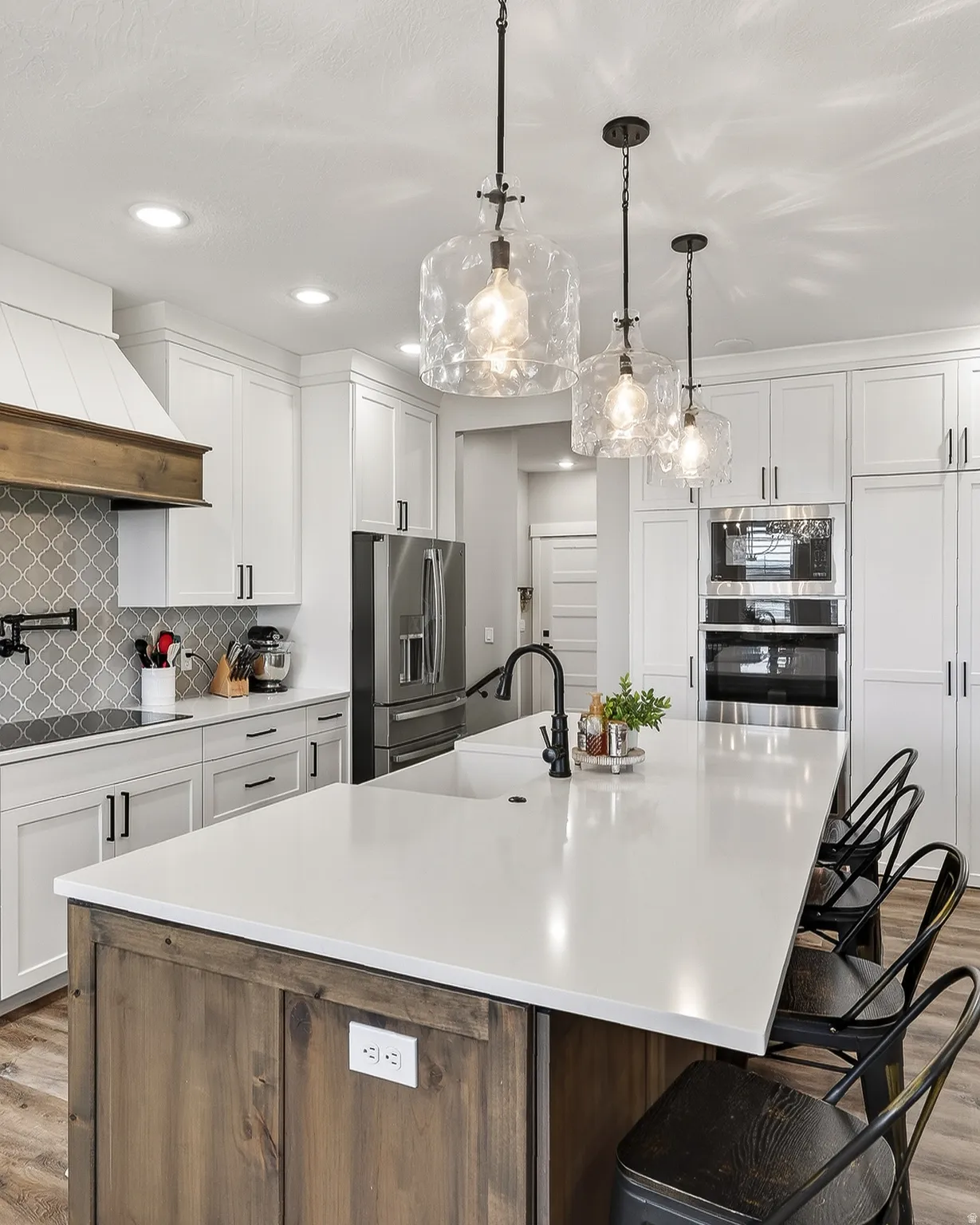 Kitchen featuring light wood-style flooring, a kitchen island with sink, a kitchen bar, two tone cabinetry, and pendant lighting