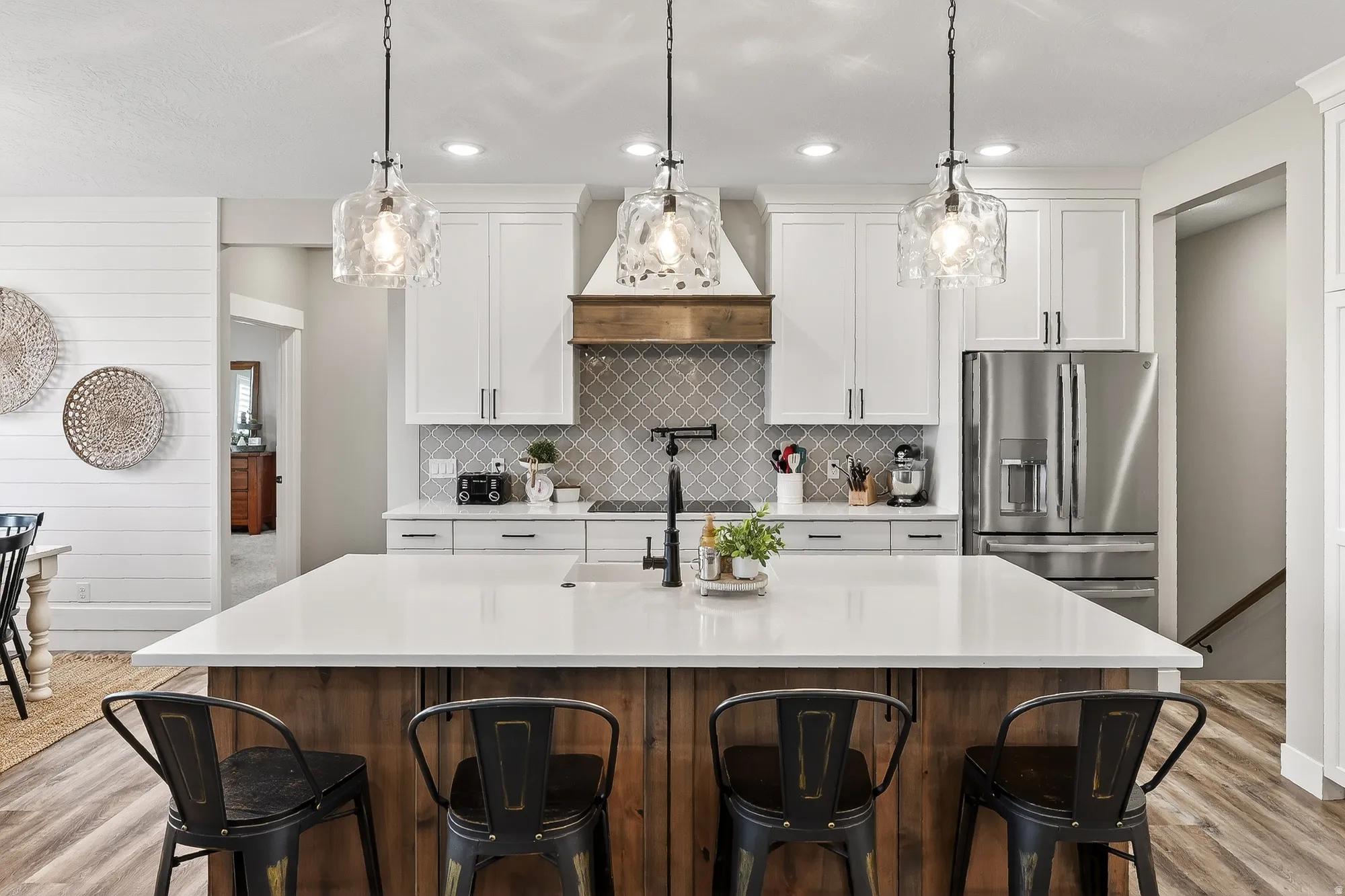 Kitchen with light wood-style floors, a kitchen breakfast bar, stainless steel fridge with ice dispenser, an island with sink, and two tone color scheme