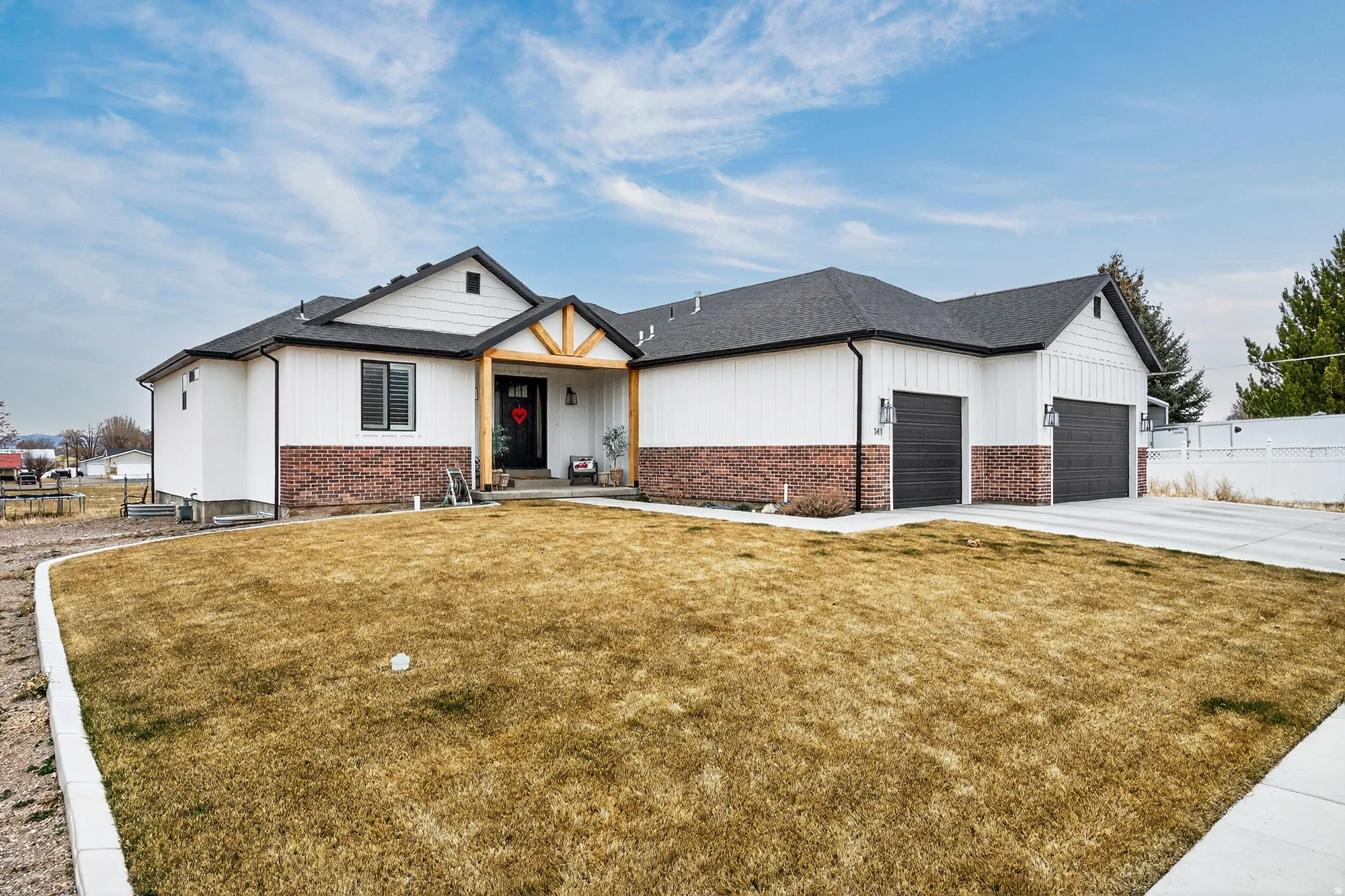 Modern inspired farmhouse with covered porch, concrete driveway, brick siding, an attached garage, and roof with shingles