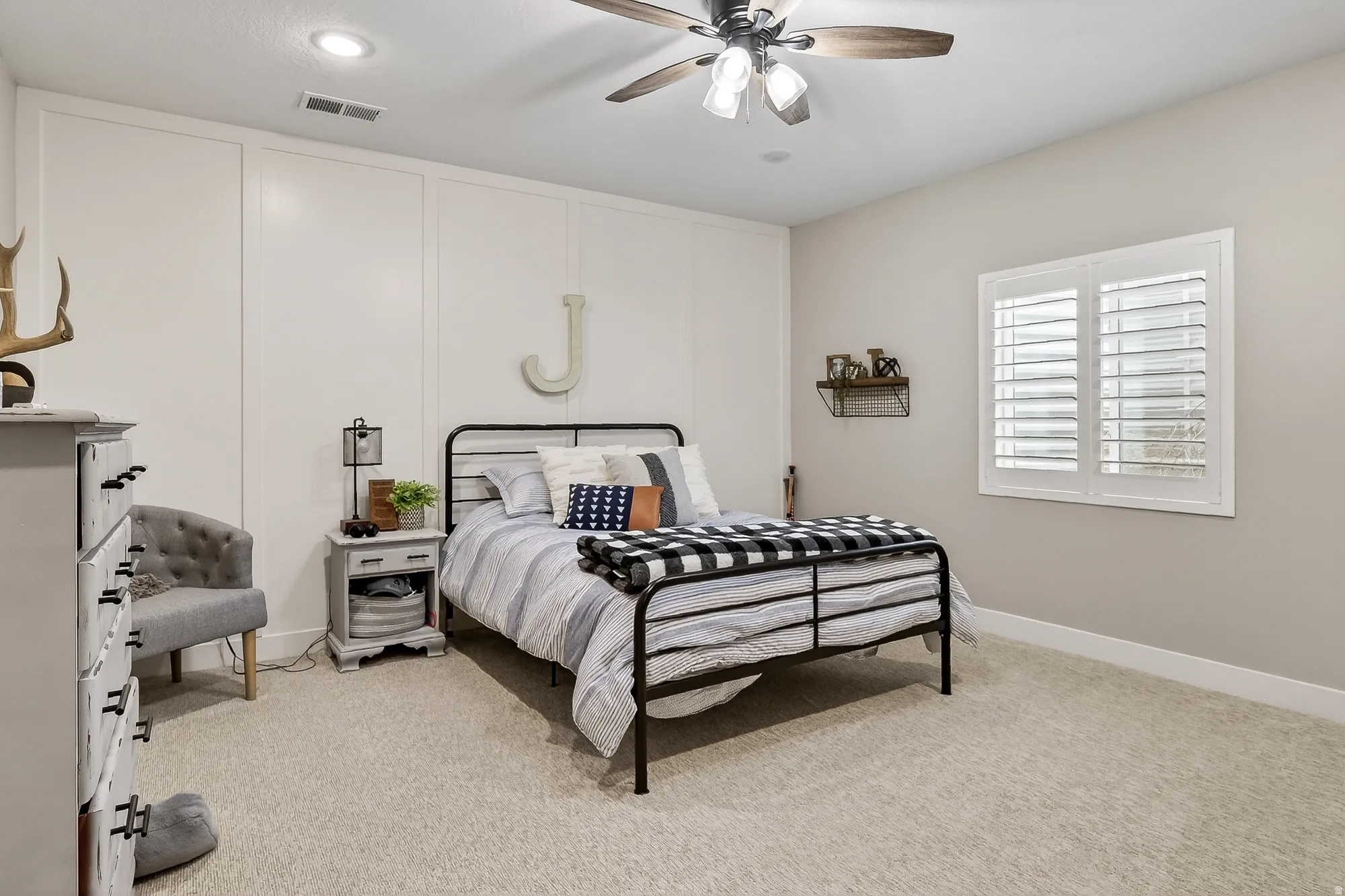Bedroom featuring light colored carpet, ceiling fan, and a decorative wall