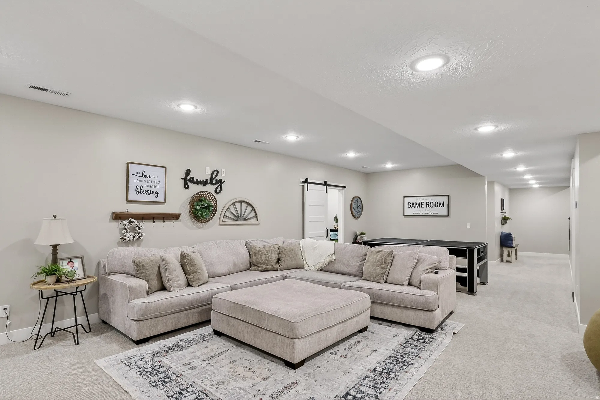 Living area featuring a barn door, light carpet, and recessed lighting