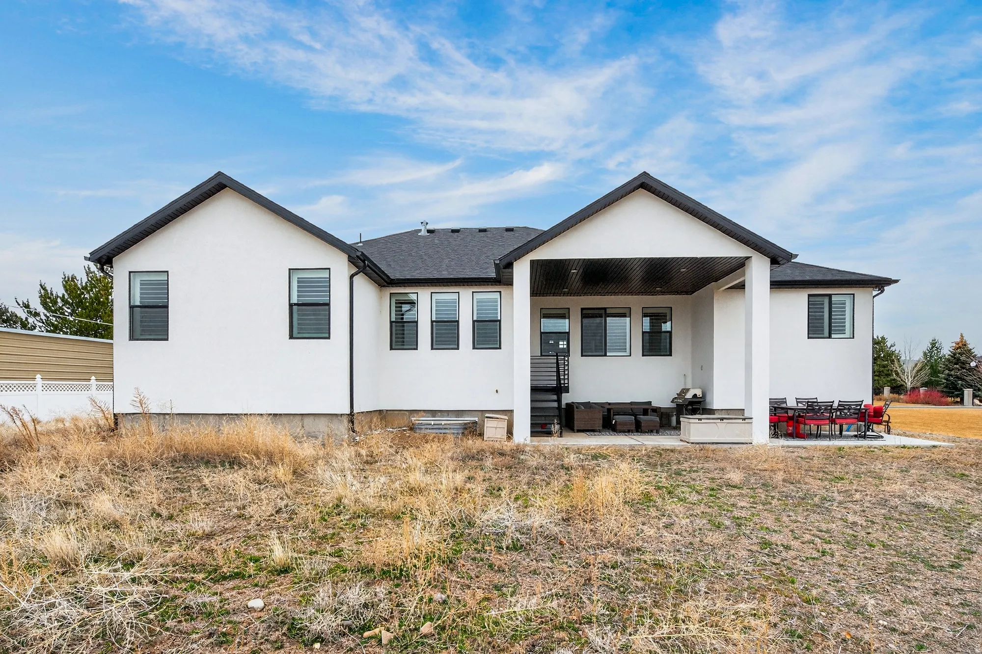 Back of property featuring a patio area, stucco siding, an outdoor hangout area, and roof with shingles
