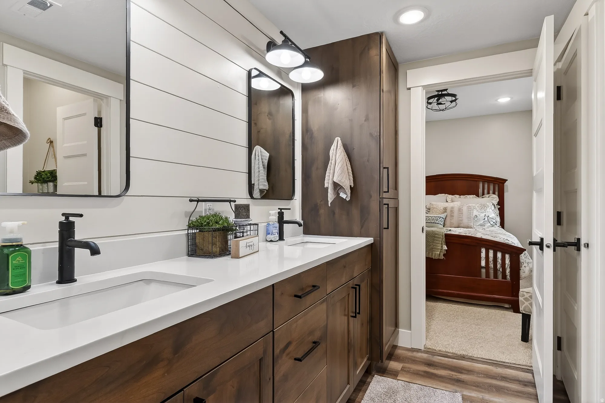 Ensuite bathroom featuring double vanity, dark wood finished floors, and recessed lighting