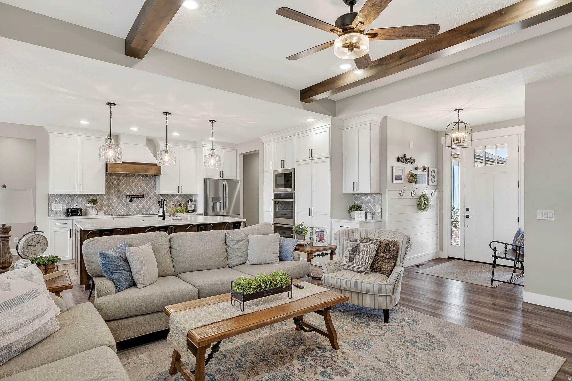 Living room with beamed ceiling, wood finished floors, a ceiling fan, and a chandelier