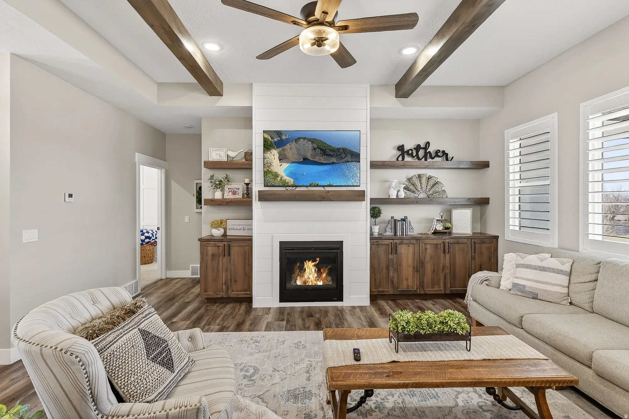 Living area with beamed ceiling, a ceiling fan, dark wood-type flooring, a fireplace, and recessed lighting