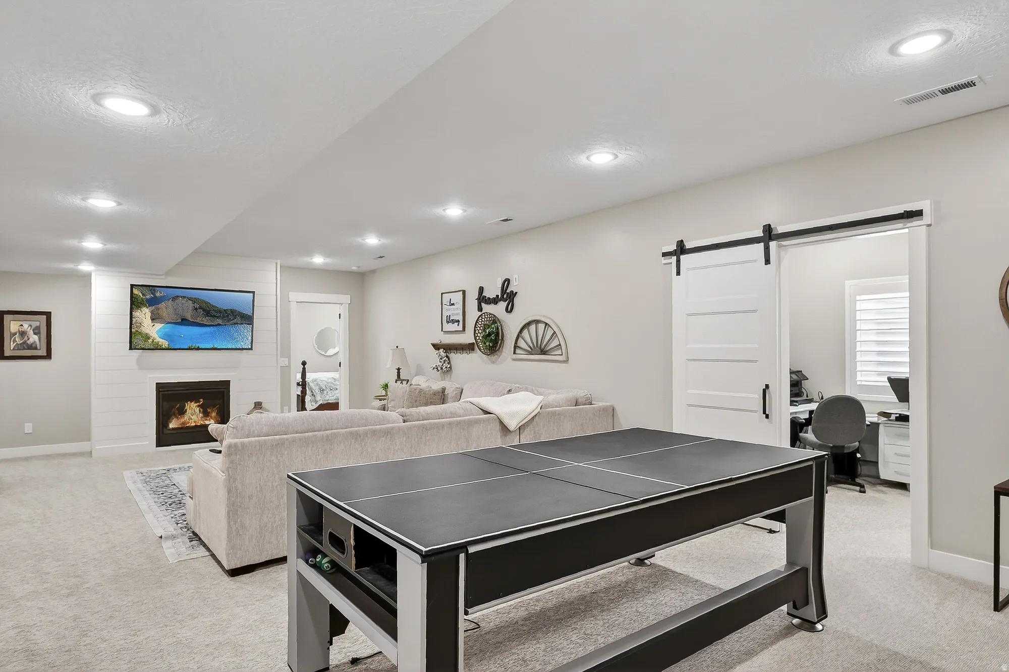 Playroom with a barn door, light colored carpet, a desk, recessed lighting, and a large fireplace