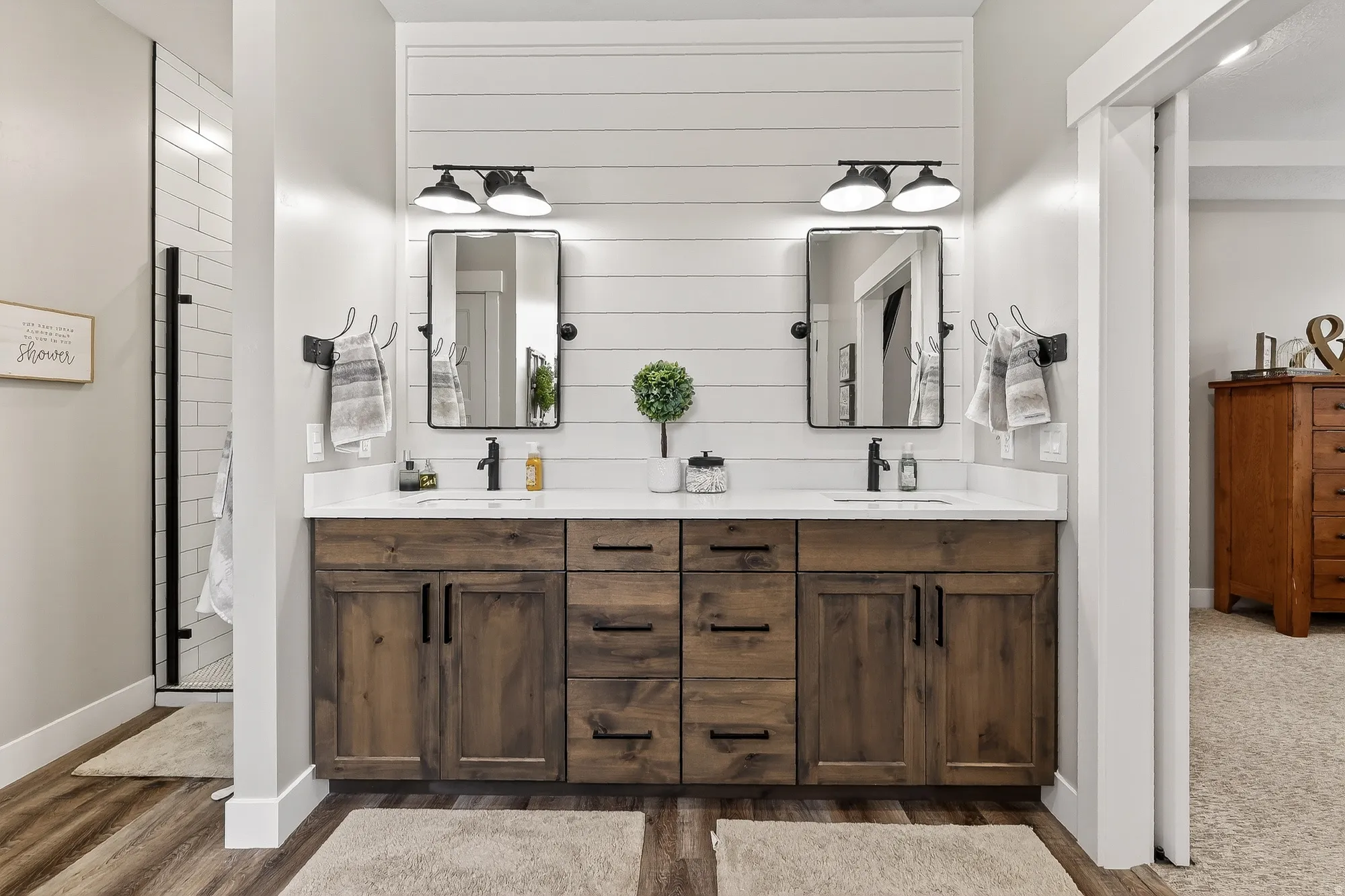 Bathroom with double vanity, an enclosed shower, and dark wood finished floors