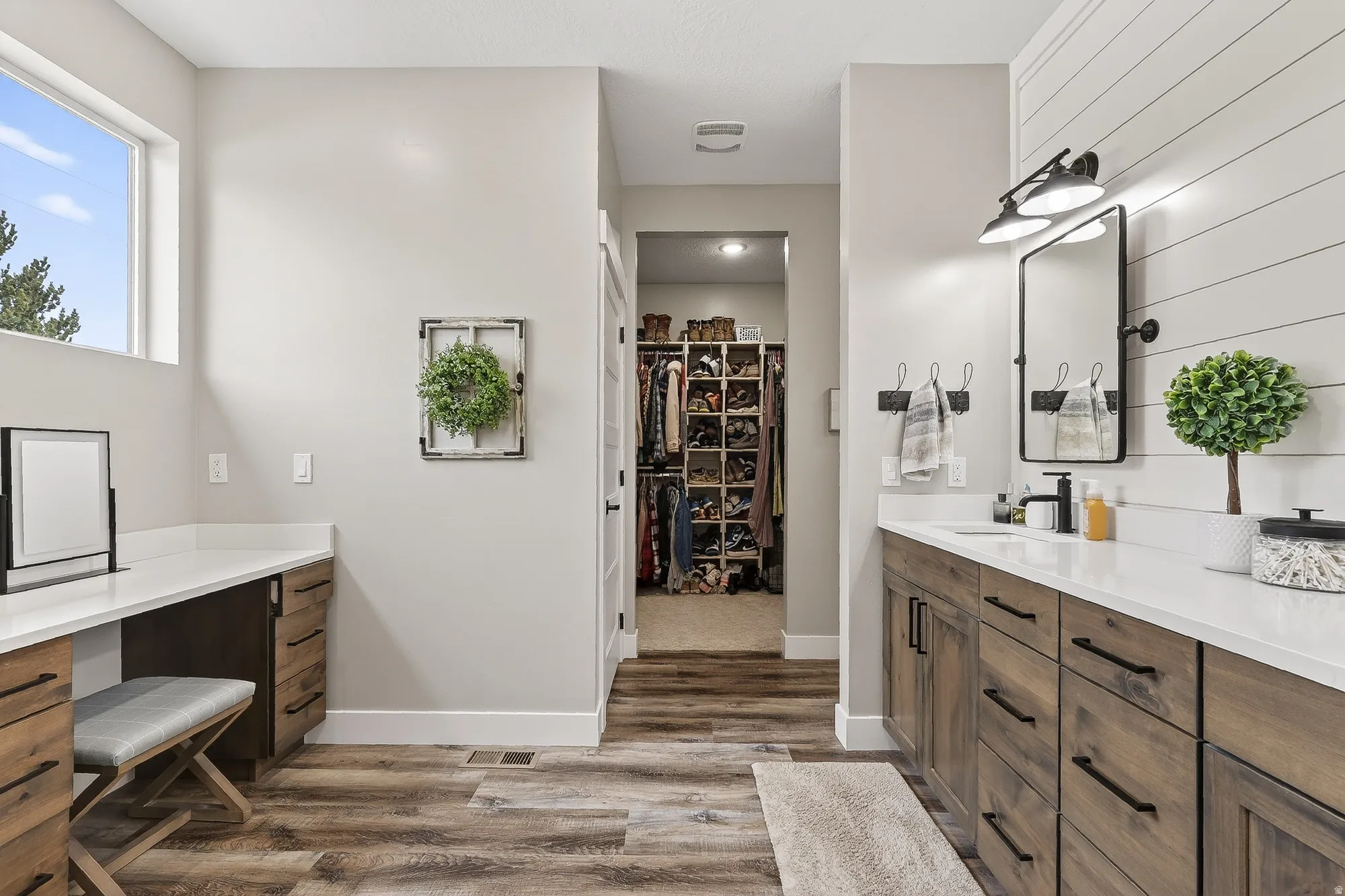 Bathroom with a walk in closet, vanity, and light wood-style floors