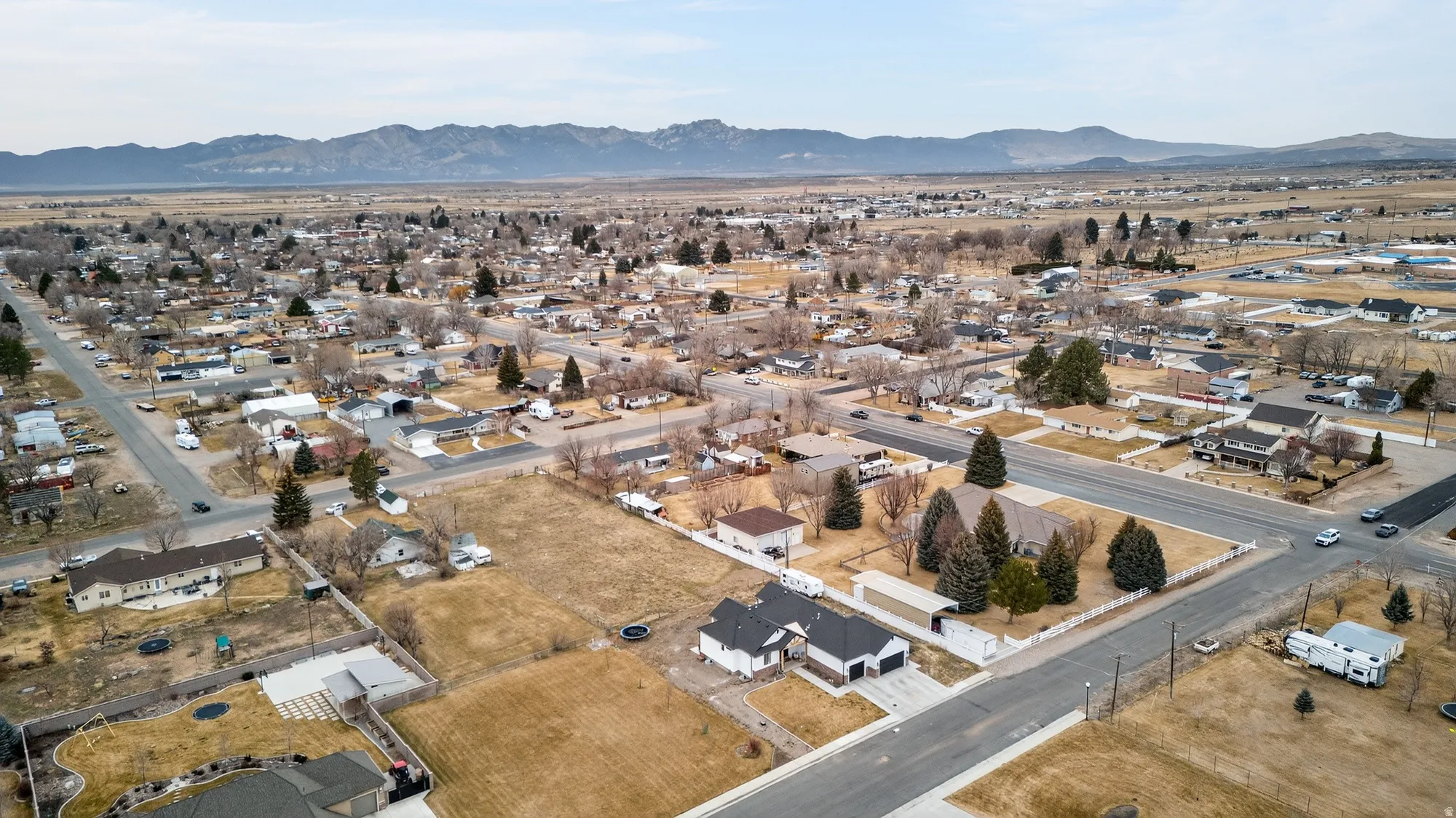 Aerial view of property and surrounding area with nearby suburban area and a mountain backdrop