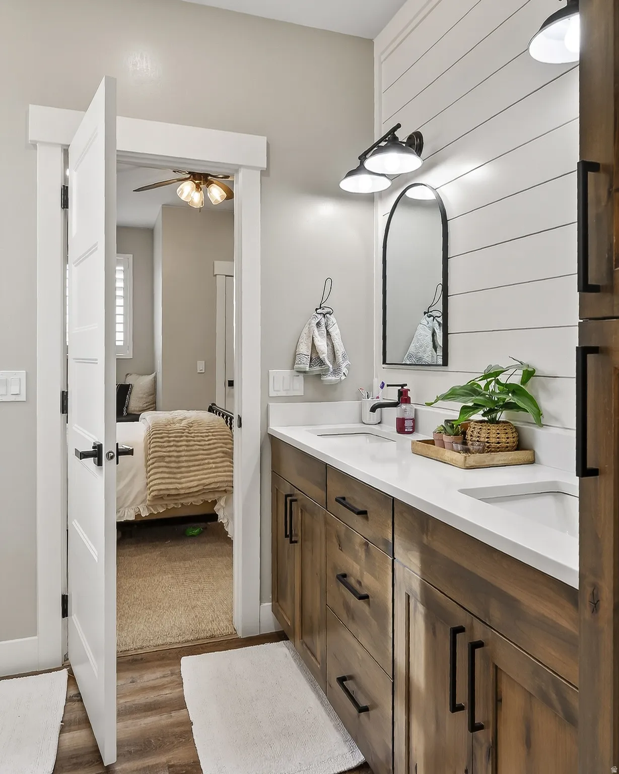 Full bath with double vanity, ensuite bath, dark wood-style floors, and a ceiling fan