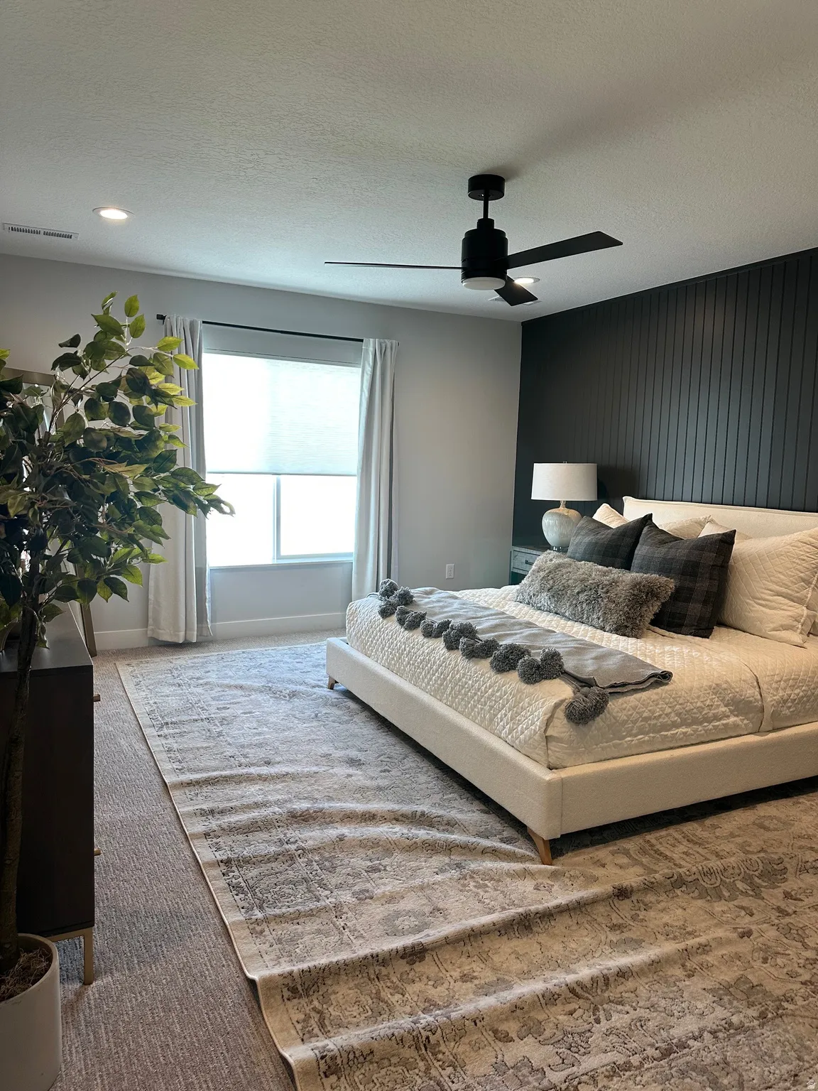 Carpeted bedroom with ceiling fan and a textured ceiling