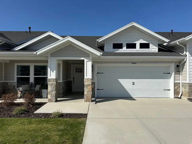 Craftsman-style home featuring stone siding, roof with shingles, driveway, covered porch, and a garage