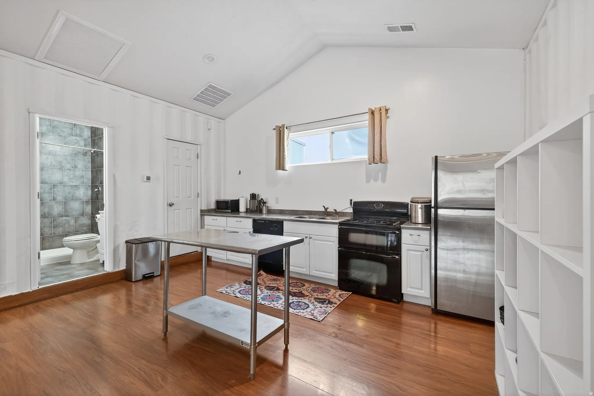 Kitchen featuring black appliances, white cabinetry, and light wood-type flooring
