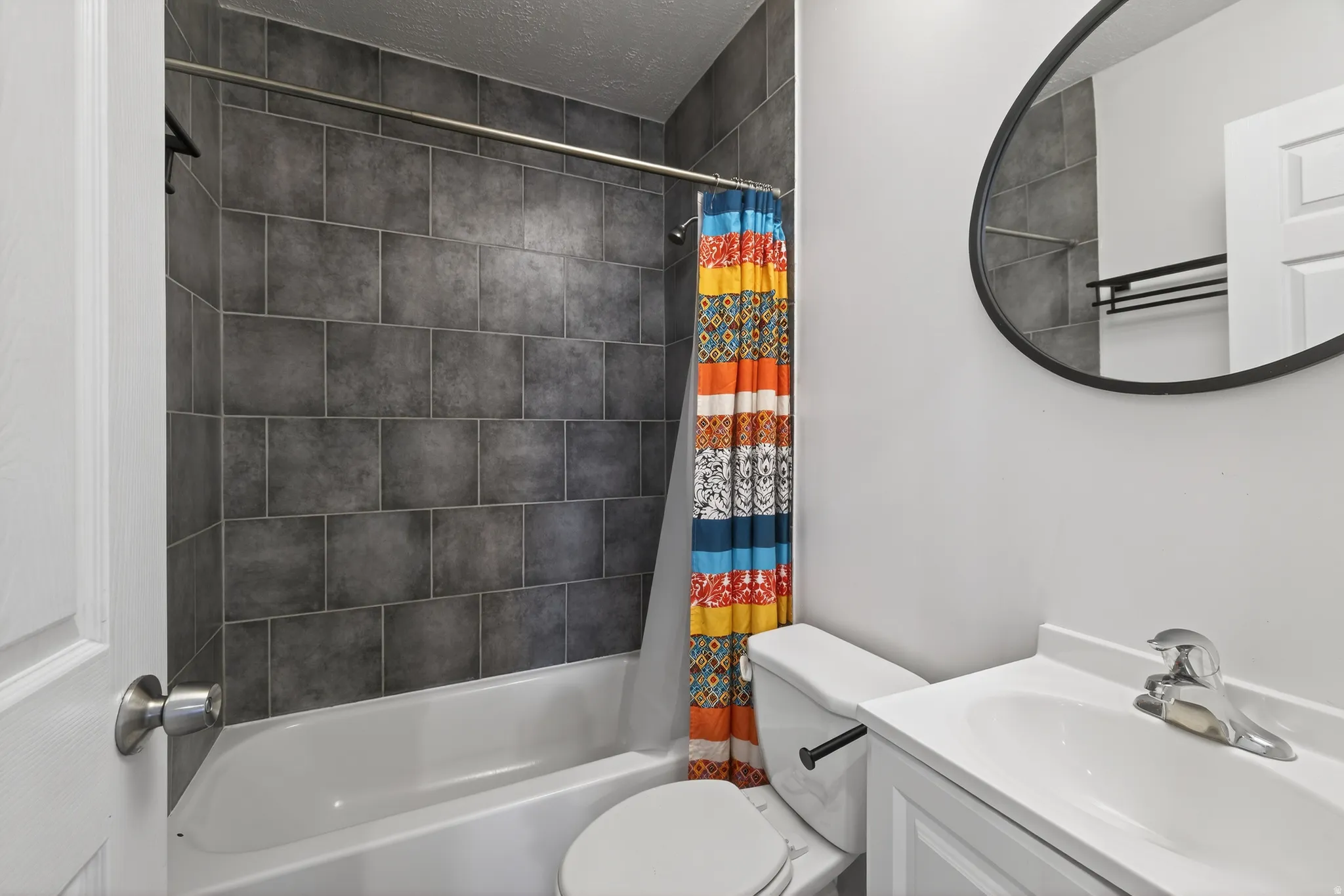 Full bath with vanity, shower / bathtub combination with curtain, and a textured ceiling