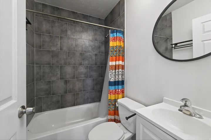 Full bath with vanity, shower / bathtub combination with curtain, and a textured ceiling