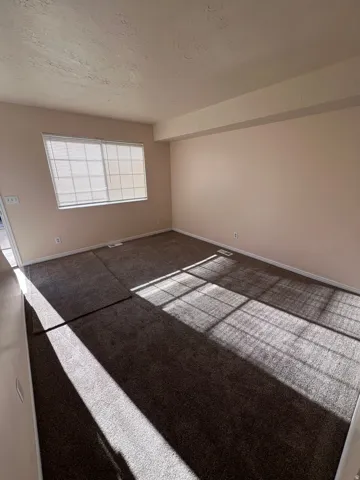 Carpeted spare room with a textured ceiling and baseboards