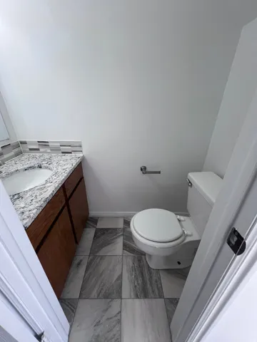 Half bath featuring vanity and light marble finish floors