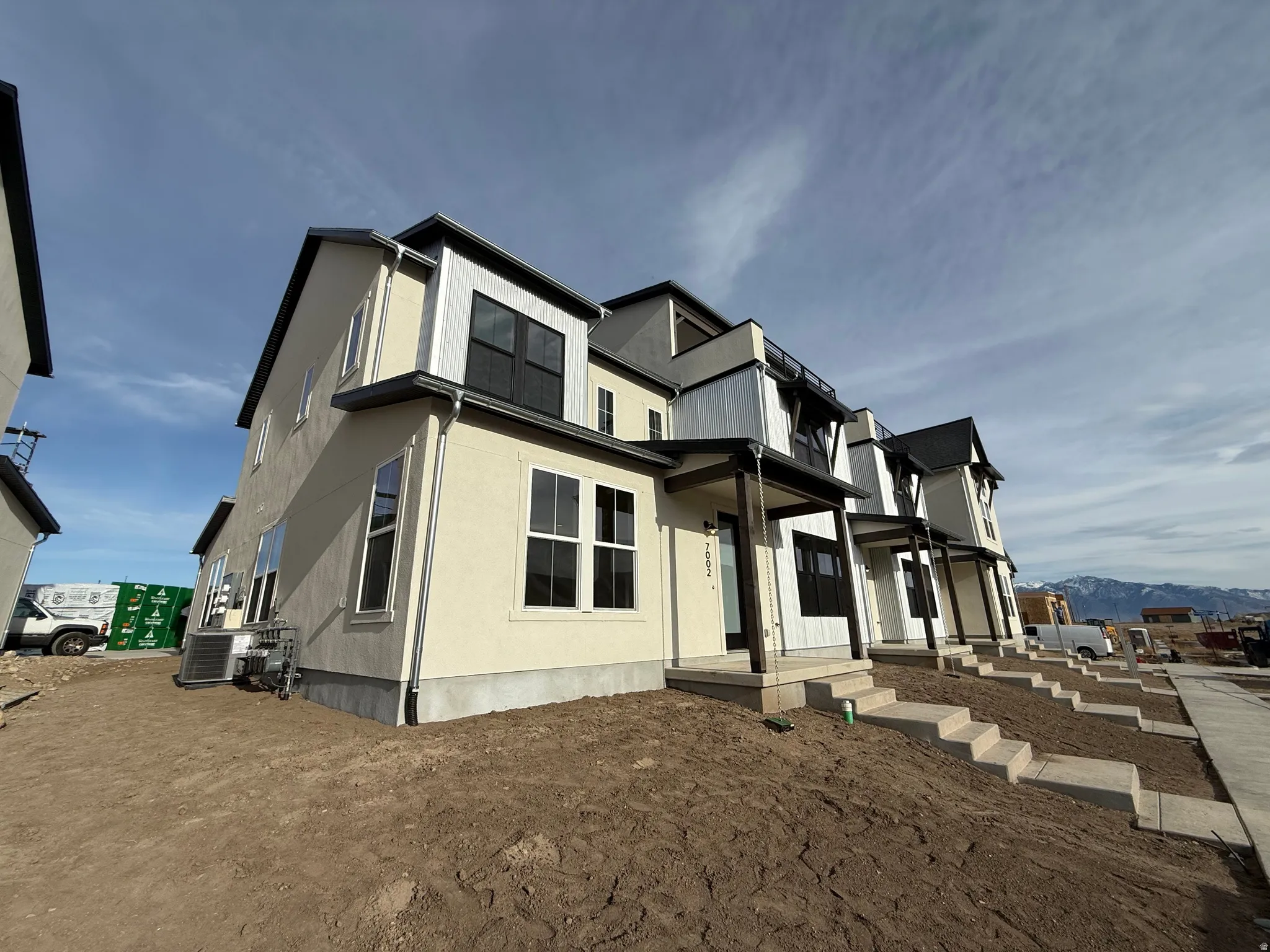 View of home's exterior featuring stucco. asphalt shingle roof, and corrugated metal