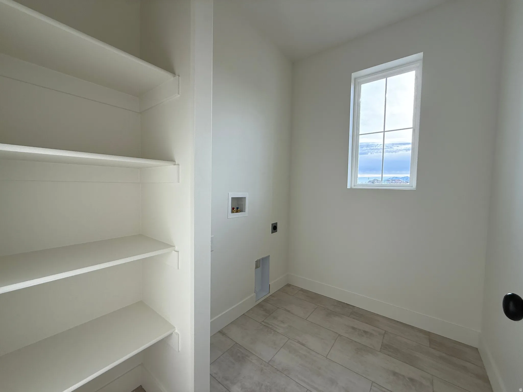 Laundry area featuring hookup for a washing machine and electric dryer hookup and shelving