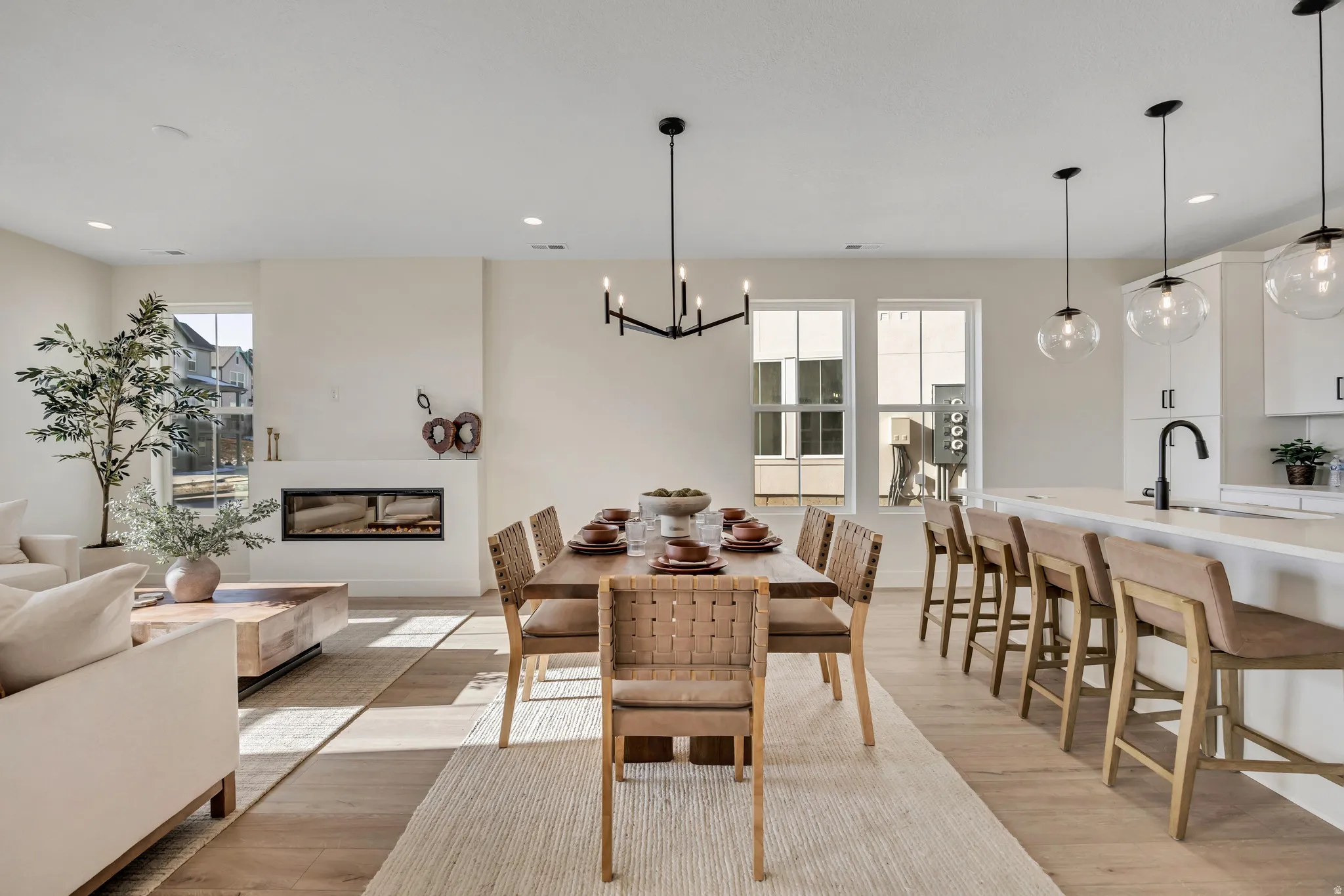 Dining room with light wood-type flooring, a glass covered fireplace, recessed lighting, and a chandelier