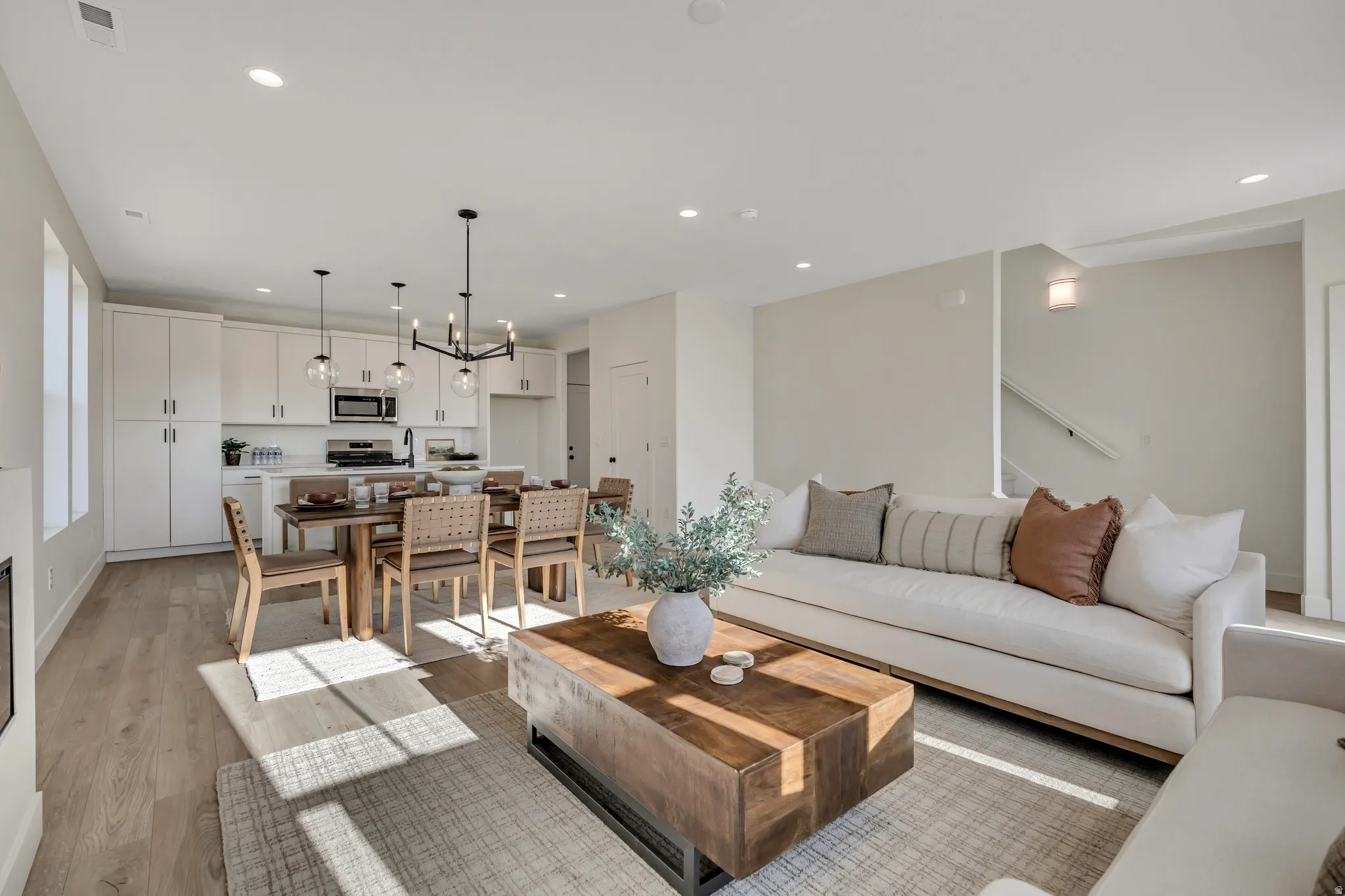 Living area with light wood finished floors, recessed lighting, a chandelier, and stairs