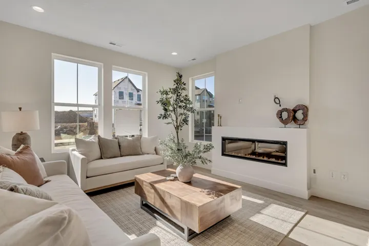 Living room featuring wood finished floors, a glass covered fireplace, and recessed lighting