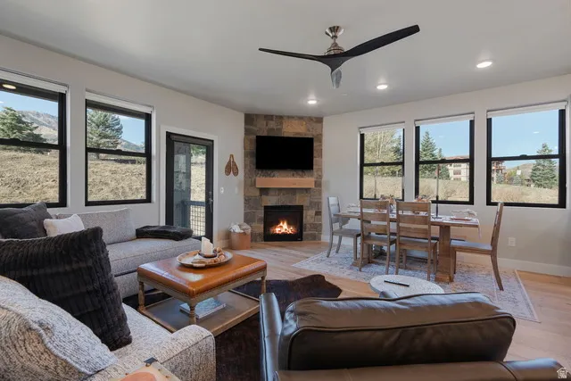 Living room featuring a stone fireplace, wood finished floors, recessed lighting, and a ceiling fan