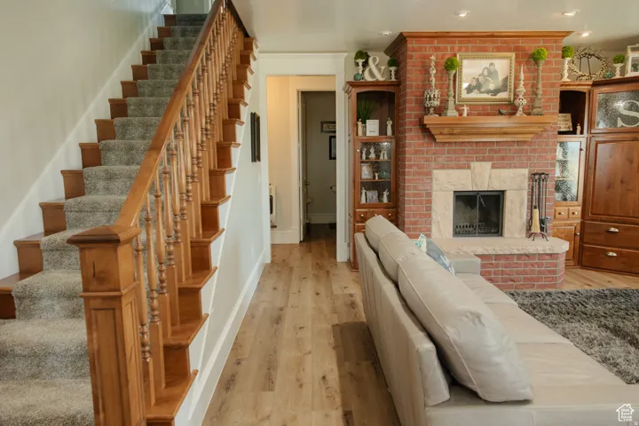Living area featuring light wood-type flooring, stairway, a fireplace, and heating unit