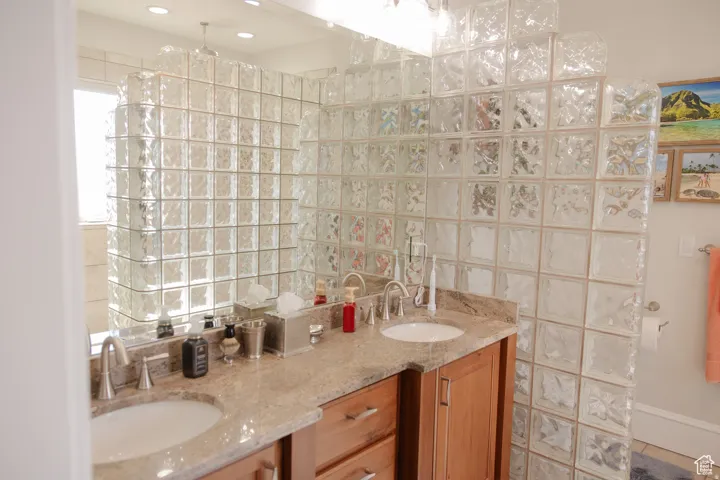 Bathroom with double vanity, a walk in shower, and tile walls
