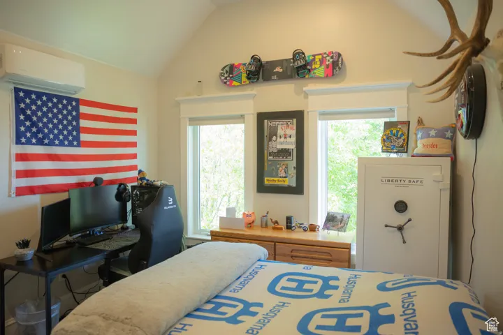 Bedroom featuring a wall mounted air conditioner and lofted ceiling