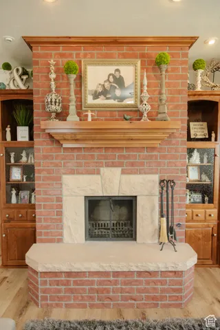 Detailed view of wood finished floors, a brick fireplace, and recessed lighting