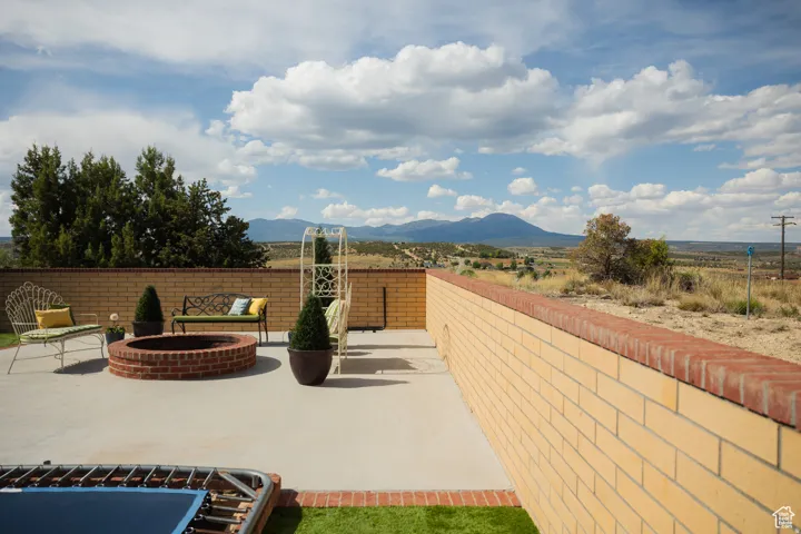 Fenced backyard featuring an outdoor fire pit, a patio area, and a mountain view