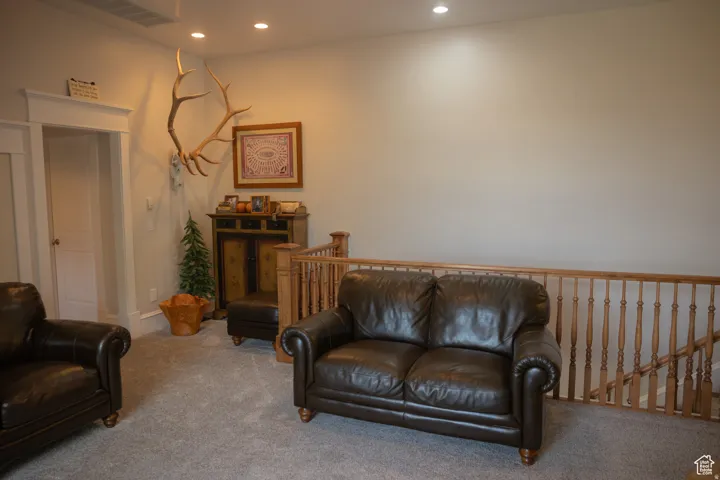 Living area featuring an upstairs landing, carpet, and recessed lighting