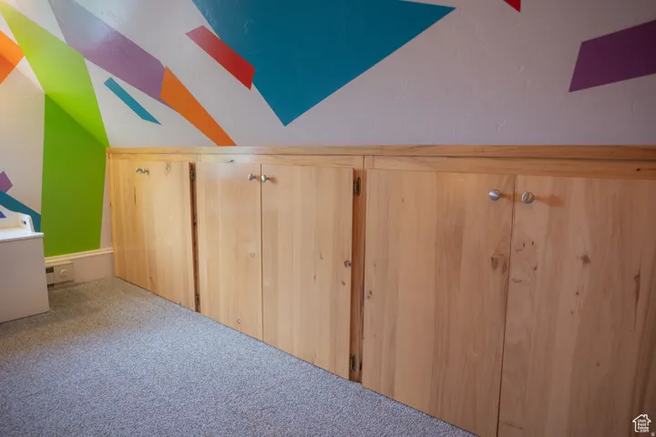 Additional living space with vaulted ceiling and carpet flooring