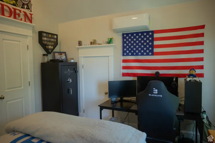 Bedroom featuring a wall unit AC and a desk