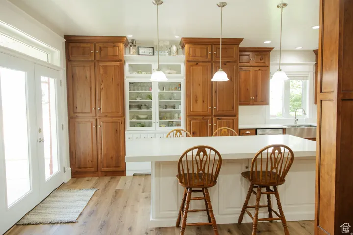 Kitchen featuring a kitchen breakfast bar, light countertops, brown cabinetry, light wood-style floors, and pendant lighting