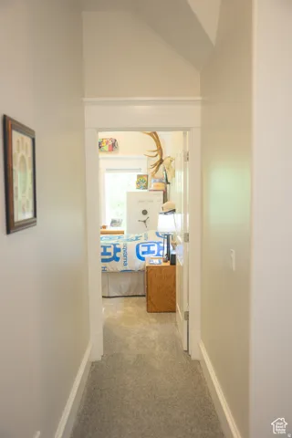 Hall with carpet flooring and lofted ceiling