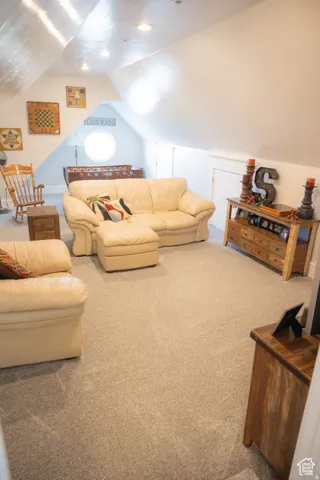 Living area with carpet flooring and vaulted ceiling