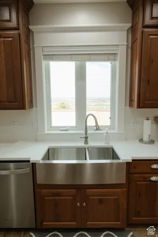 Kitchen featuring stainless steel dishwasher, light countertops, and healthy amount of natural light