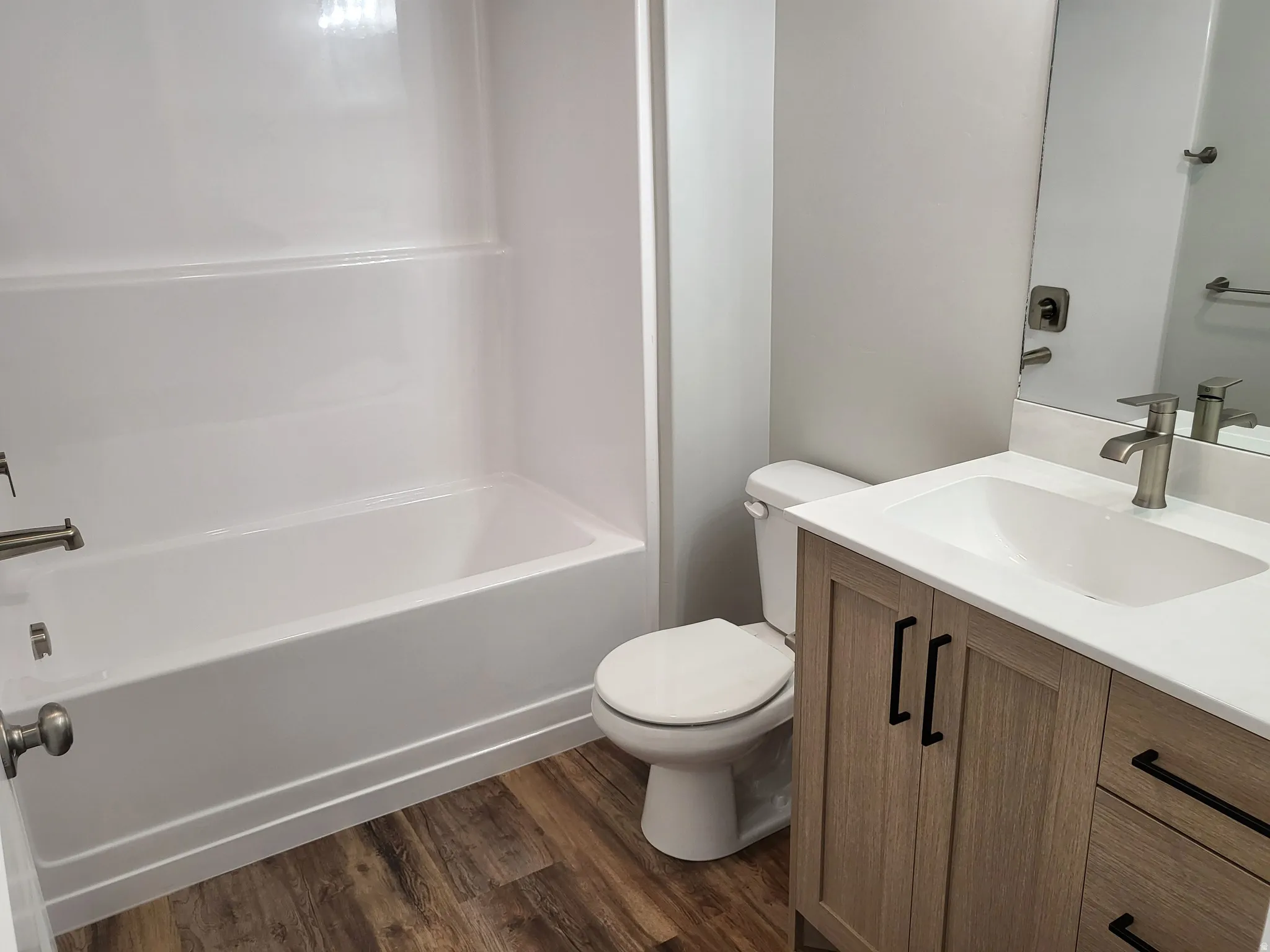 Full bathroom with vanity, dark wood-style flooring, and shower / bath combination