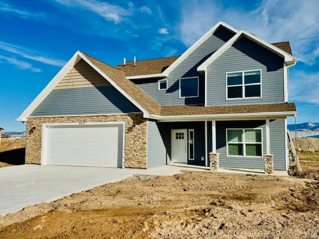 Craftsman-style home with a garage, concrete driveway, a shingled roof, stone and vinyl siding