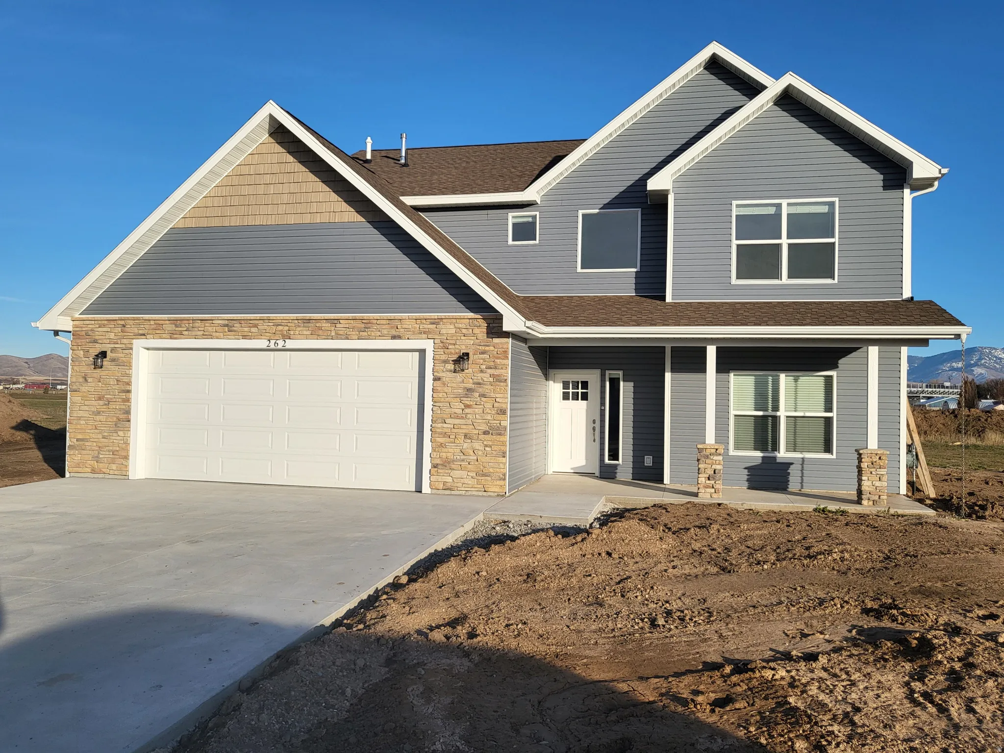 View of front of home with a shingled roof, concrete driveway, stone  and vinyl siding, and a garage