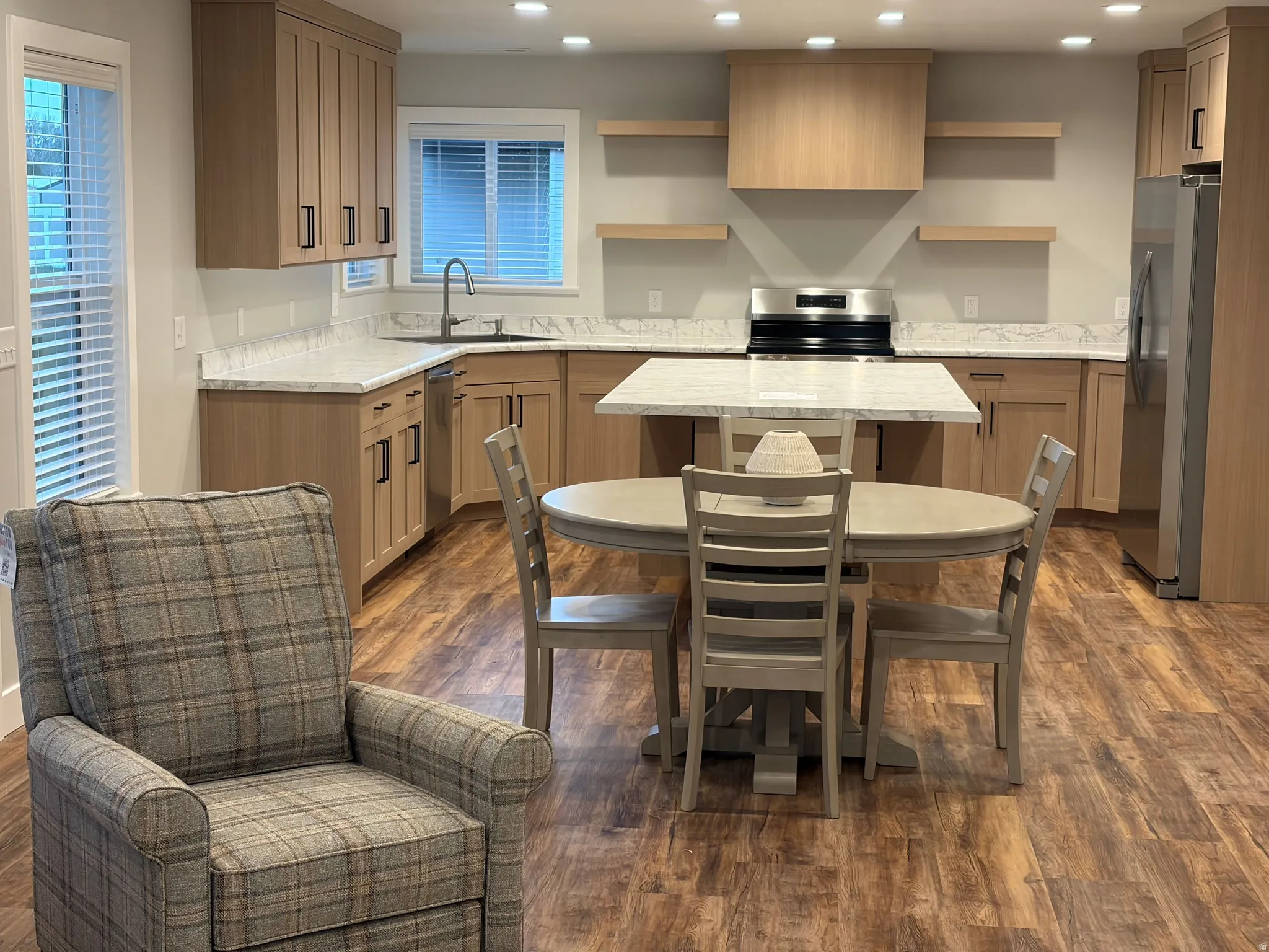 Kitchen with stainless steel appliances, a kitchen island, dark wood finished floors, recessed lighting, and light stone counters