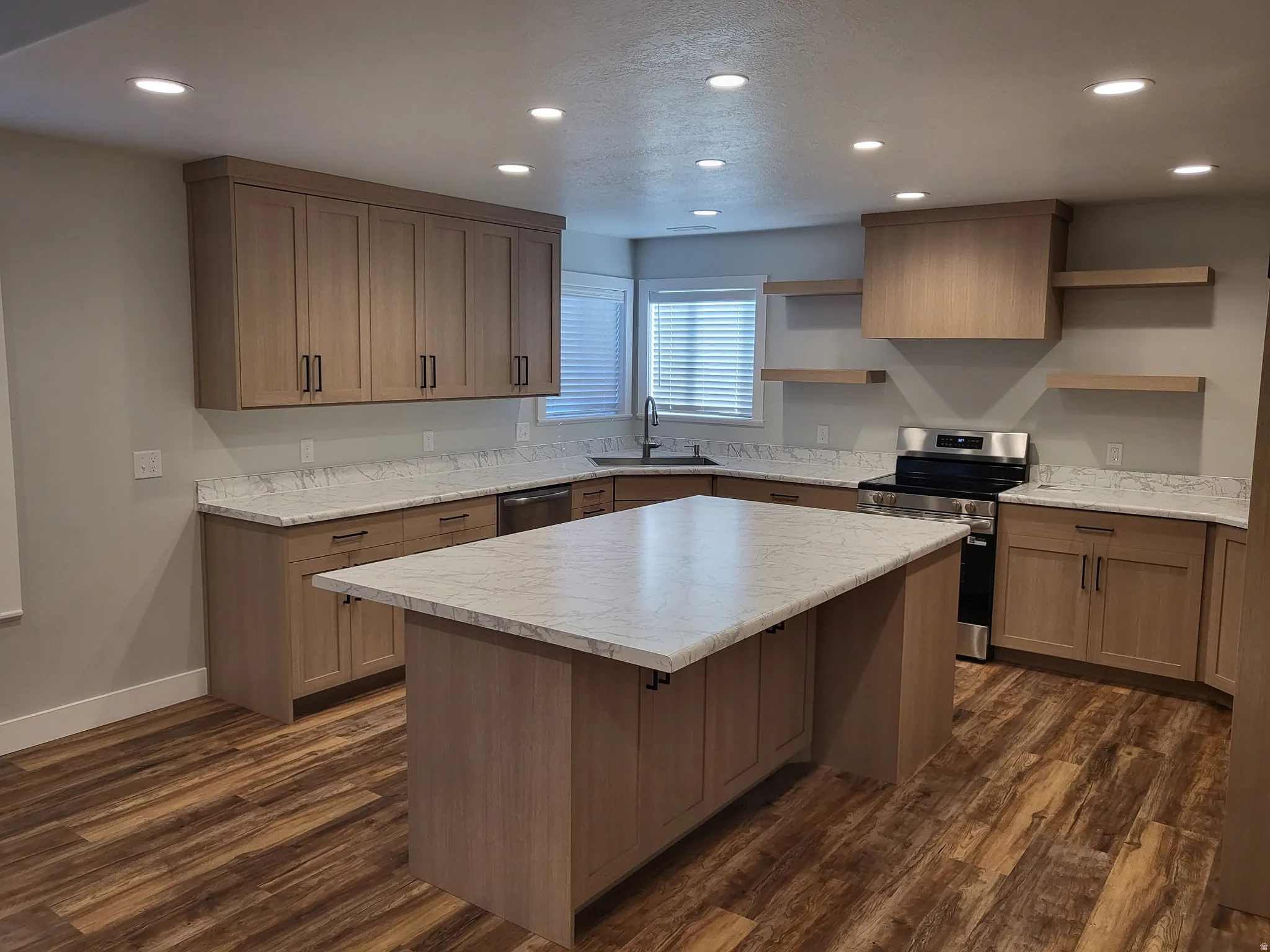 Kitchen featuring recessed lighting, appliances with stainless steel finishes, a center island, light countertops, and a textured ceiling