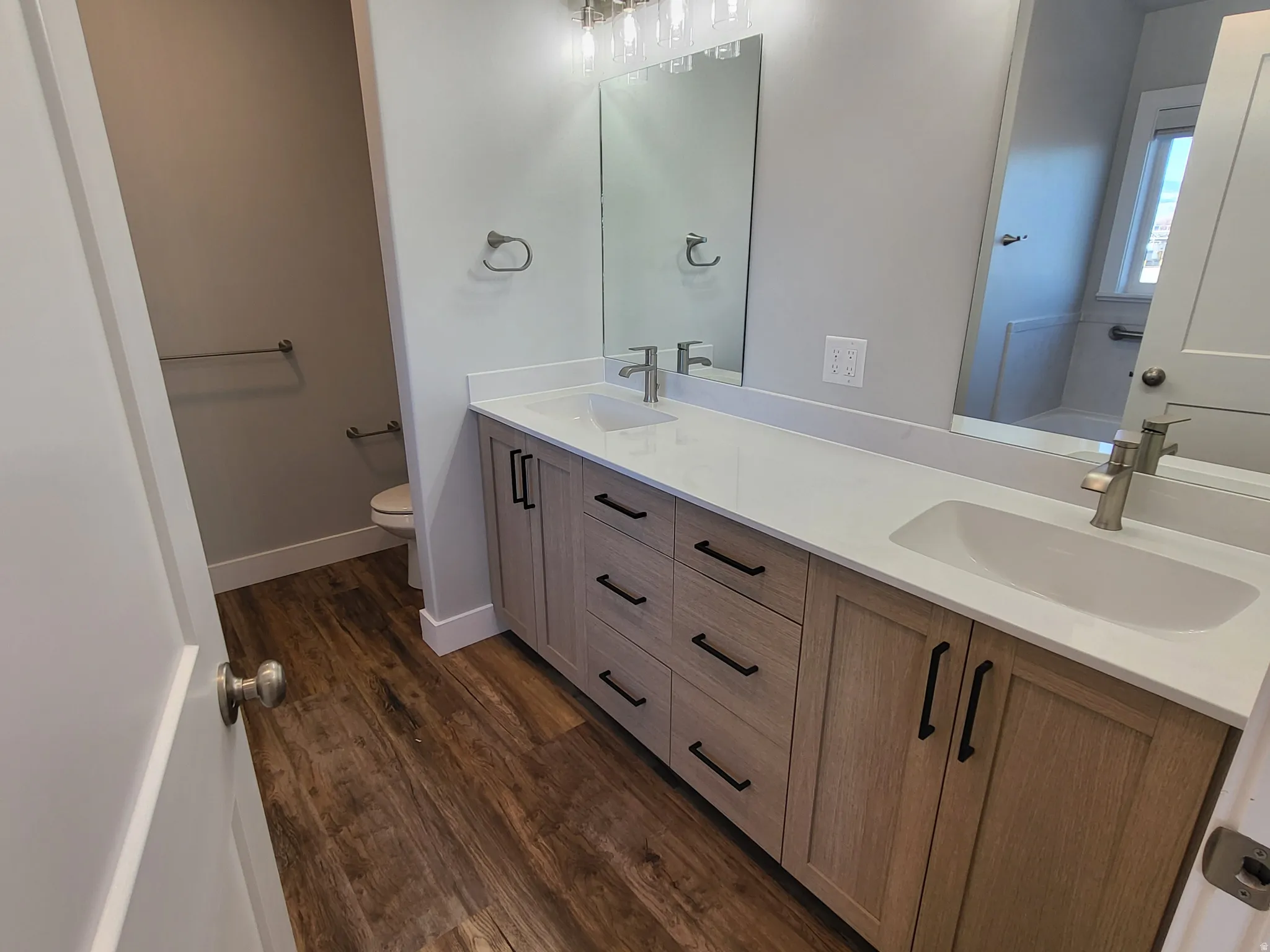 Bathroom featuring double vanity, dark wood-style flooring, and a tub to relax in