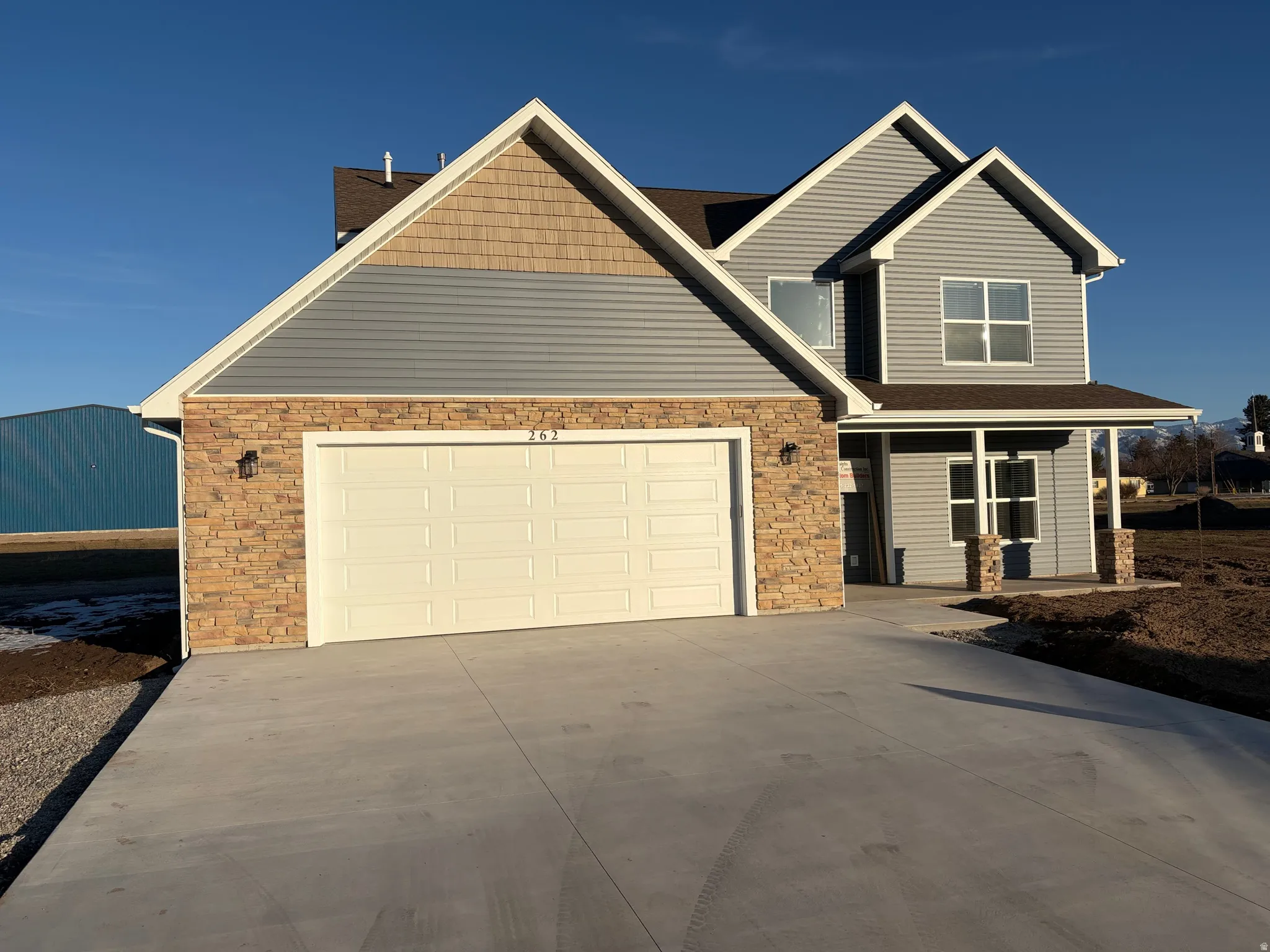 Craftsman house featuring stone siding and concrete driveway