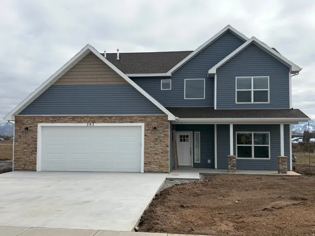 View of front of property featuring a porch, roof with shingles, concrete driveway, and stone siding