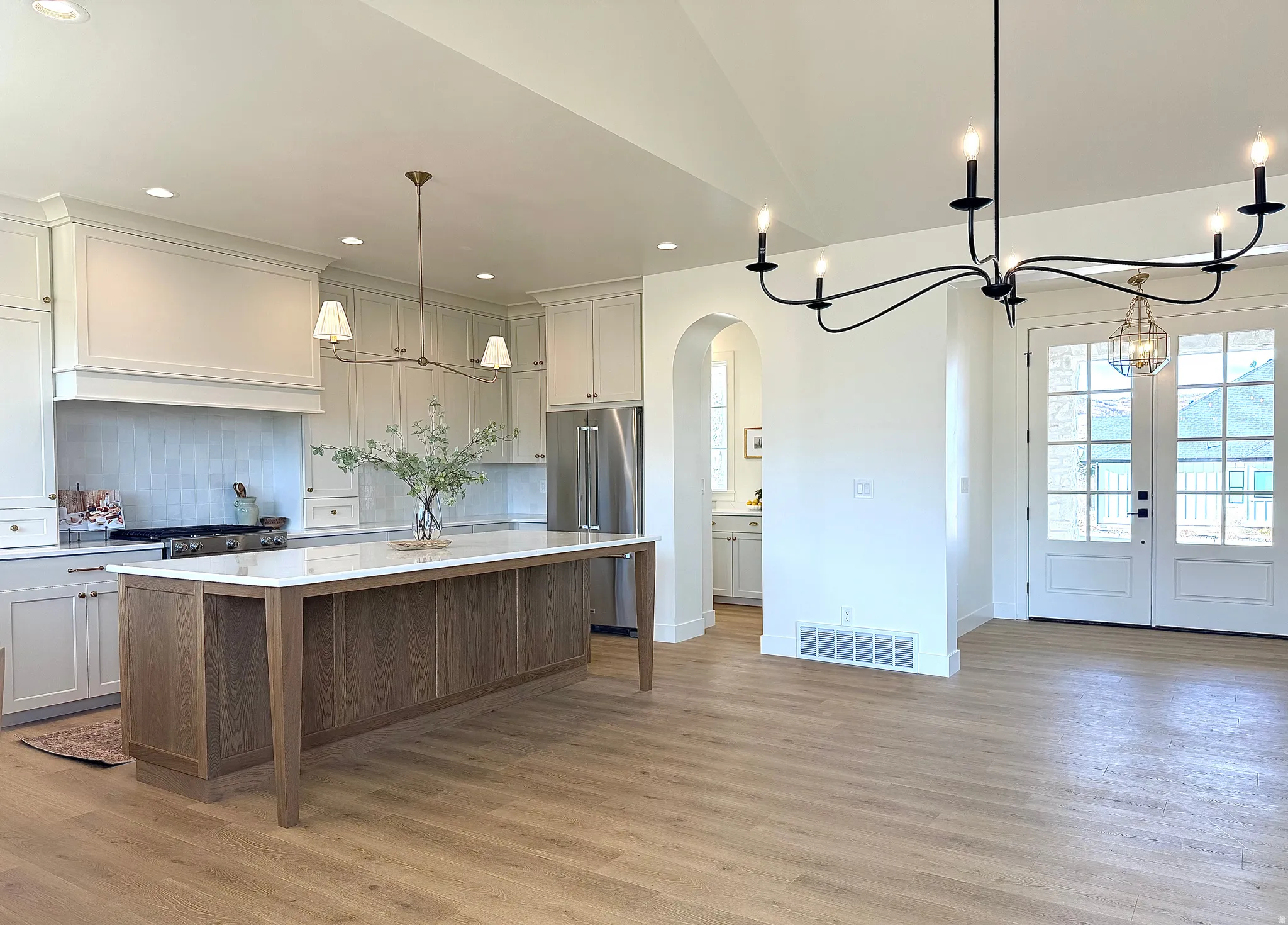 Kitchen featuring a center island, high end refrigerator, arched walkways, hanging light fixtures, and a chandelier