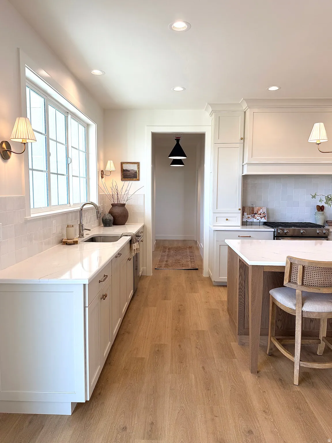Kitchen featuring tasteful backsplash, quartz countertops, white oak cabinetry, a breakfast bar, and light wood finished floors