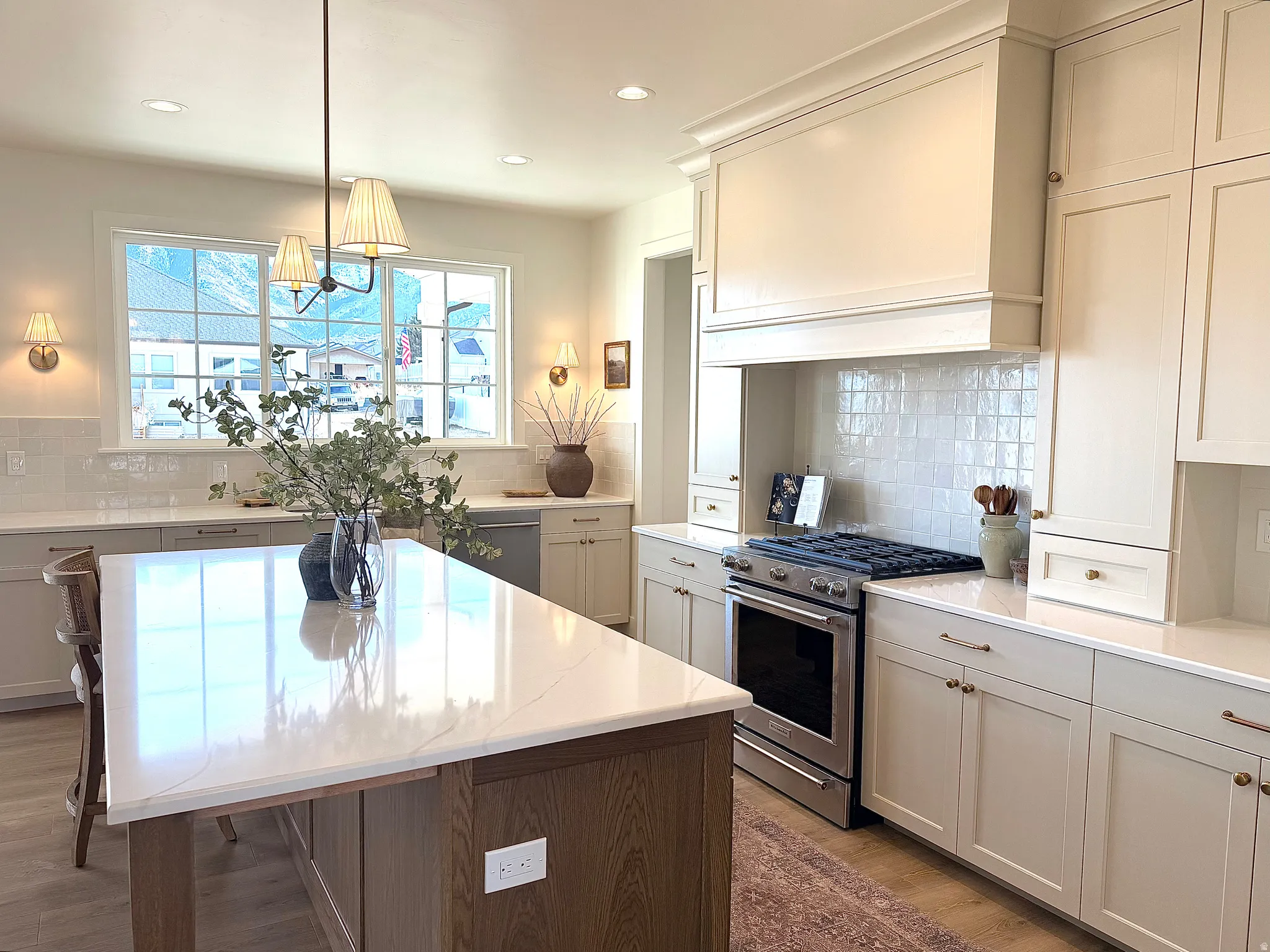 Kitchen with Kitchen Aid stainless steel appliances, backsplash, hood vent, pendant lighting, and a center island